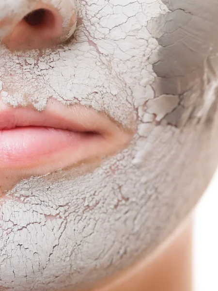 Woman applying clay mask on face.