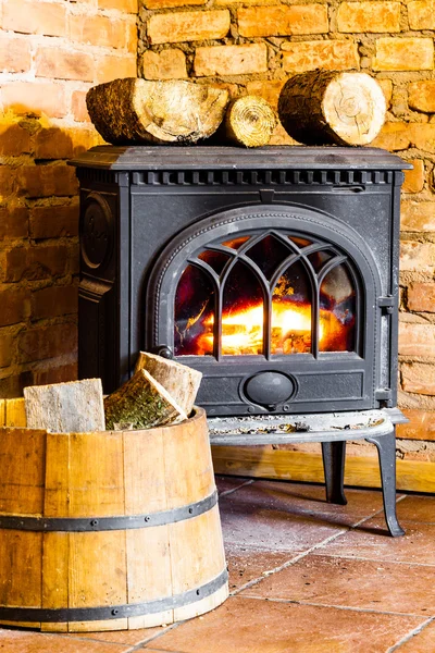 Fireplace with fire flame and firewood in barrel interior.