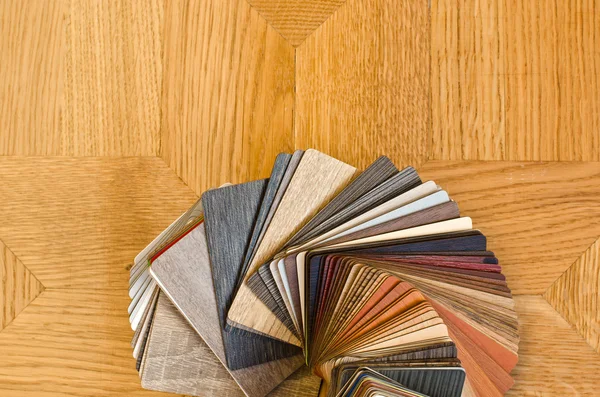 Different color samples of wood floor on brown parquet background.