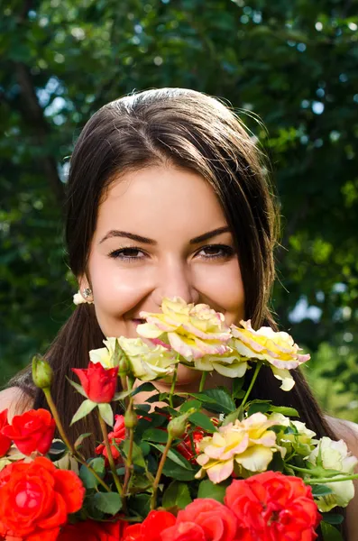 Girl smelling a bouquet of red and yellow roses on a hot summer day.