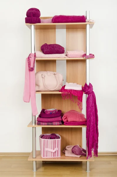 Pink clothes nicely arranged on a shelf.