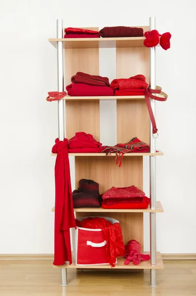 Red clothes nicely arranged on a shelf.
