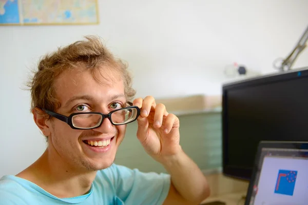Happy young computer programmer at his desk