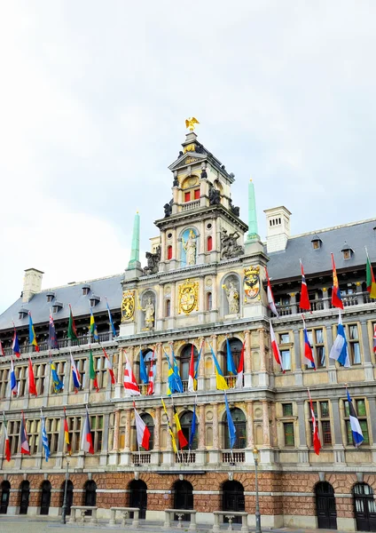 Medieval building of City Hall in Antwerp decorated with flags of different countries in rainy day