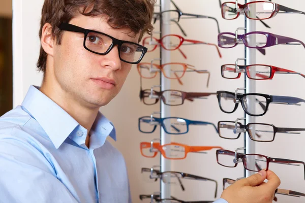 Young man at optician with glasses, background in optician shop