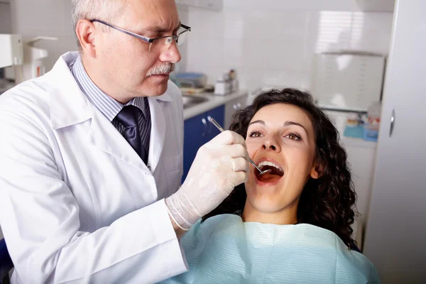 Dentist with mirror checking patient's teeth