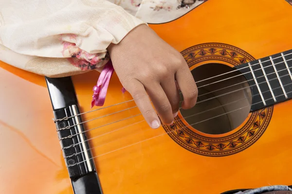 Closeup on a child\'s hand playing the guitar