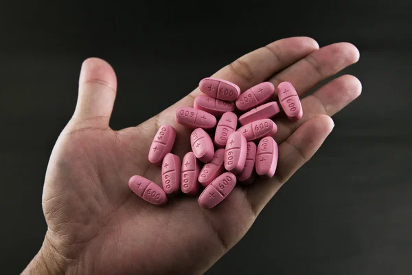 Pills in man hand on black background