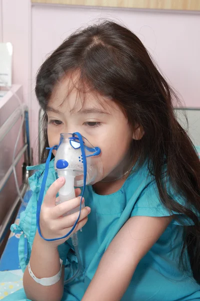 Little girl with a mask for inhaler in hospital