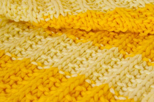 Texture of a knitted cloth of brightly yellow and orange color, in a strip