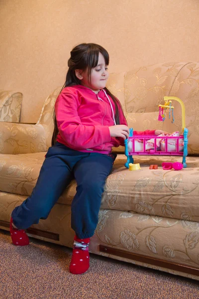 Girl on the couch, playing crib toy