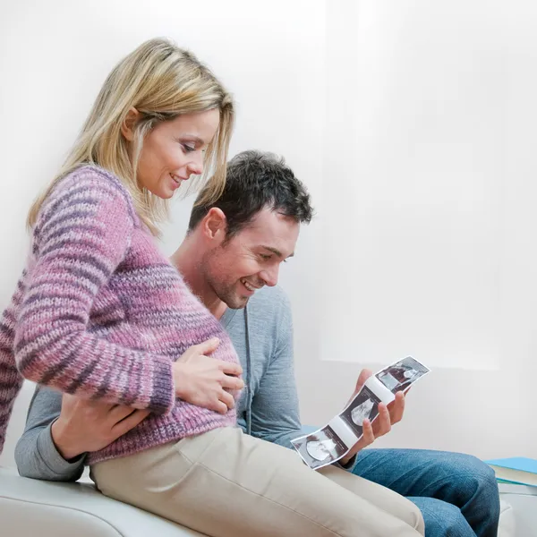 Smiling pregnant couple with ultrasound scan