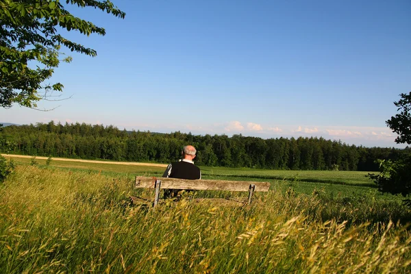 A retired man sitting on a bench reading