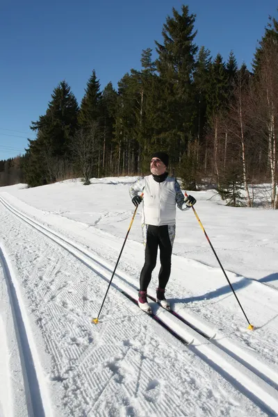 A senior man is doing cross-country skiing