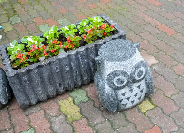 Rock owl statue with flower
