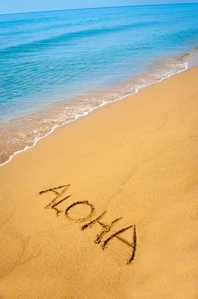 Word Aloha written in sandy on tropical beach