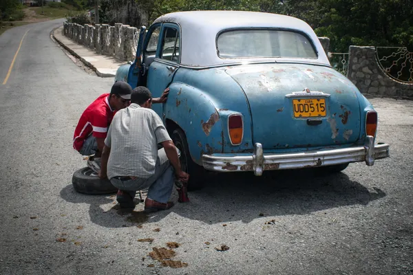 Young men changing tyre in Siboney, Cuba