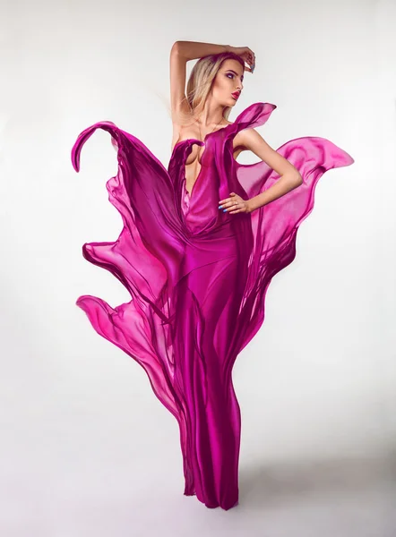Voluptuous young woman with creative pink dress in studio
