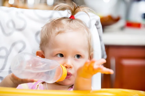 Child girl with bottle with infant formula on kitchen. Use it for child, healthy food concept