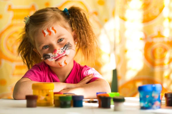 Little artist, drawing paint with paint of face.