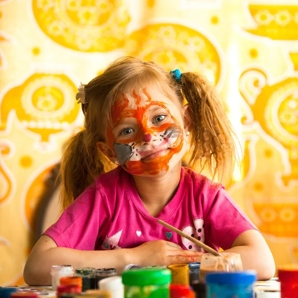 Child, drawing paint with paint of face.