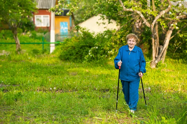 Active old woman nordic walking outdoors (85 years)