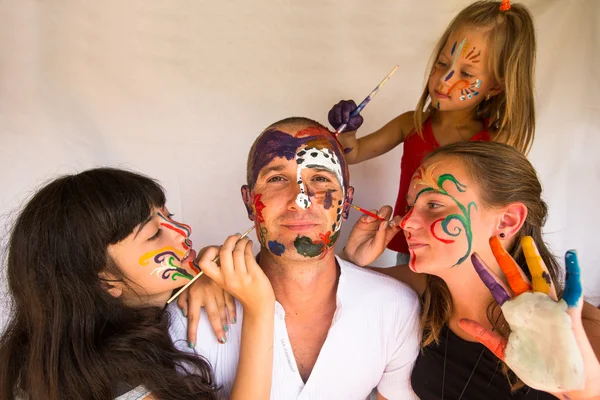 Happy family - children paints face of his father