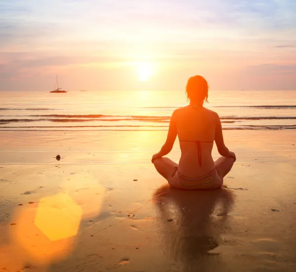 Woman yoga on sea sunset