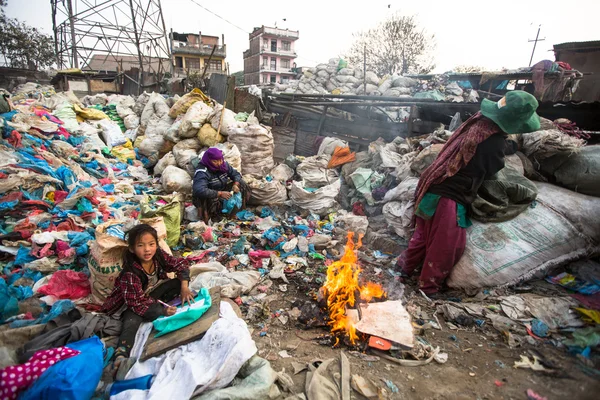 Unidentified child is sitting while her parents are working on dump