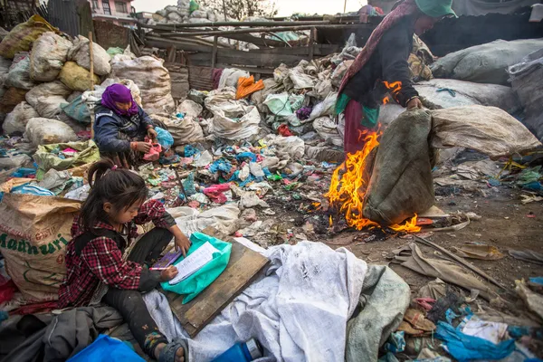 Unidentified child is sitting while her parents are working on dump