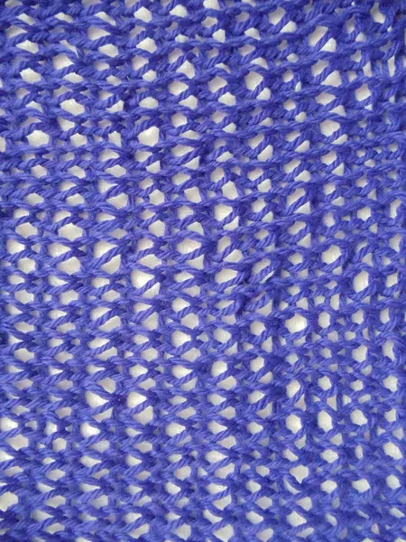 Background. A blue handmade knitted woolen fabric with a seamless fishnet pattern ona white background.