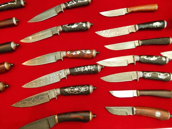 Hunting knives with decorative elements on the red background.Moscow International Exhibition \