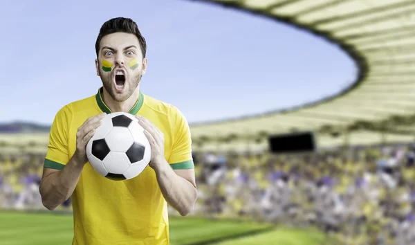 Brazilian soccer player holding a soccer ball celebrates on the stadium