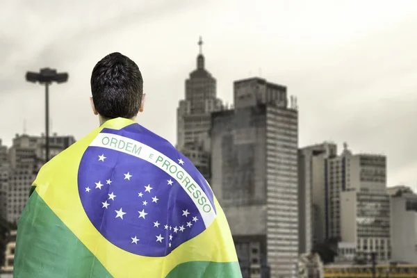 Brazilian holding a brazilian flag looks to Sao Paulo Skyline, Brazil