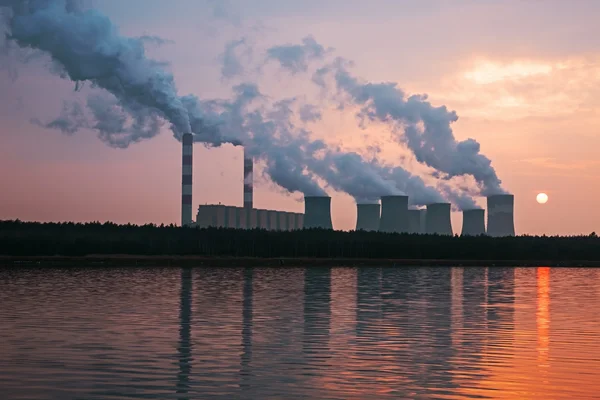 The smoke from the chimneys of a power plant at sunset