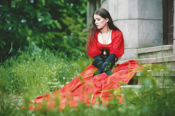 Woman in red Victorian dress sitting on stairs