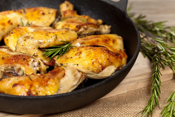 Frying pan with chicken, garlic and rosemary