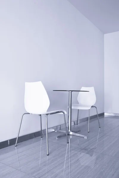 White chairs and glass table in a clean background