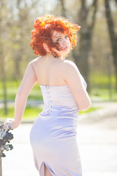 Gorgeous red-haired woman on a walk in the park. Young girl on the nature