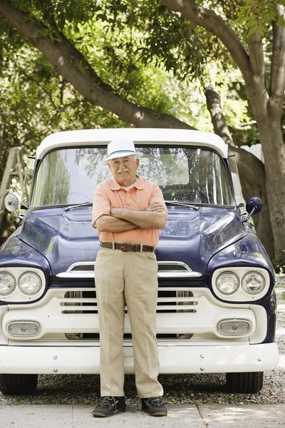 Portrait of elderly man standing in front of old pickup truck