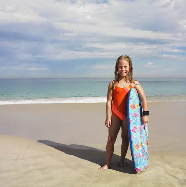 Portrait of girl holding boogie board at beach