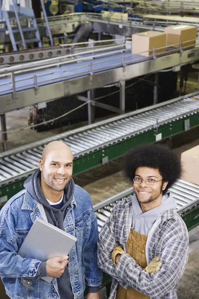 Two men standing in front of conveyor belt