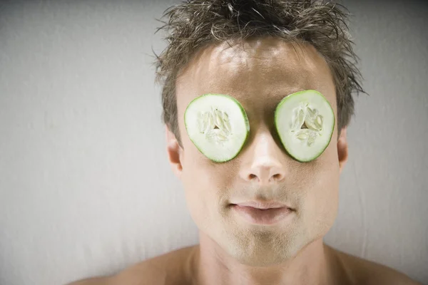 Man laying on spa table with cucumber slices on eyes