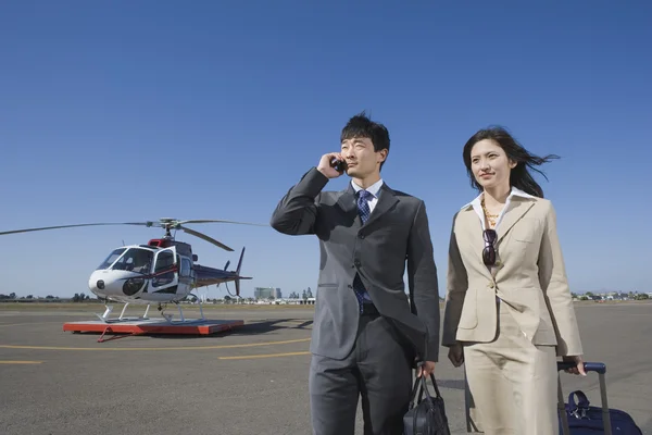 Asian businesspeople waking away from helicopter