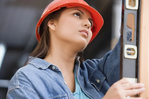Hispanic female construction worker using a level
