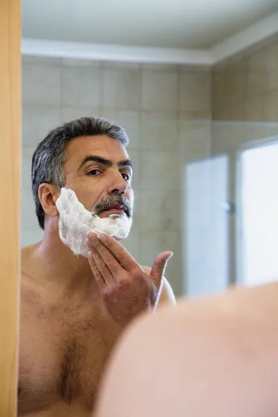 Middle-aged Hispanic man applying shaving cream