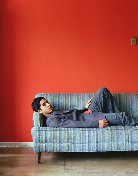 Young man lying down on couch