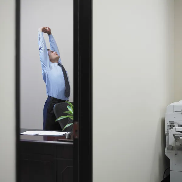 Businessman stretching in his office