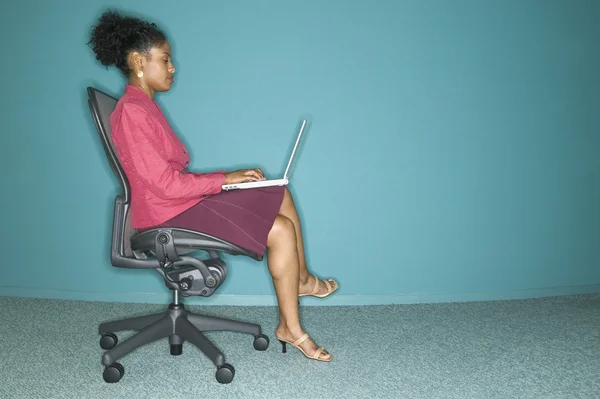 Profile of businesswoman sitting in chair with laptop