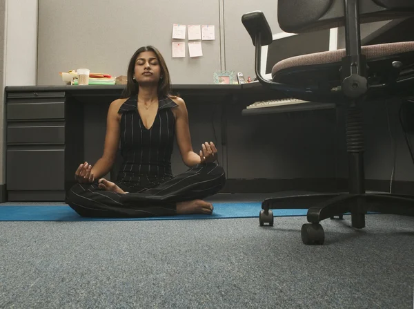 Young woman practicing yoga in office